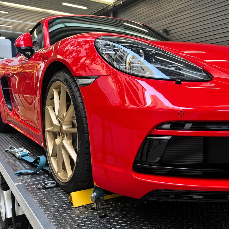 Red Porsche secured on a transporter after a Japanese auction